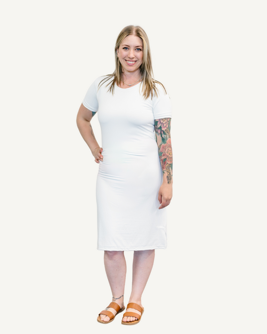 A girl in a white dress stands confidently with her hands on her hips, exuding a sense of empowerment and poise.