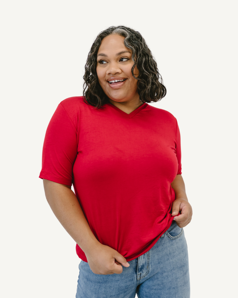 Woman in red shirt and jeans, standing confidently. Favorite Tee.
