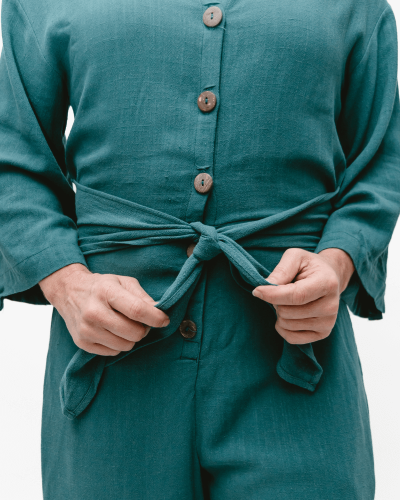 A Green linen romper with long sleeves and a tie waist. Perfect for a casual summer look.