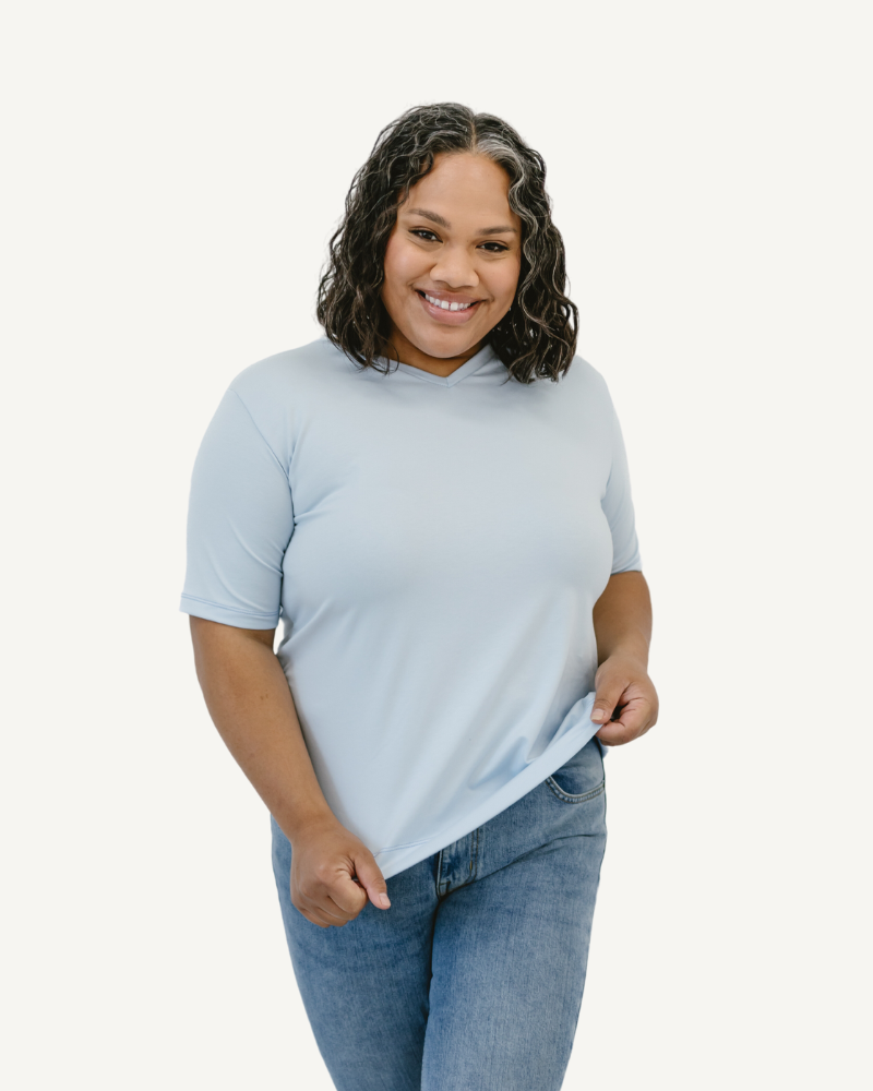 Woman in neutral shirt and jeans, standing confidently. Favorite Tee.