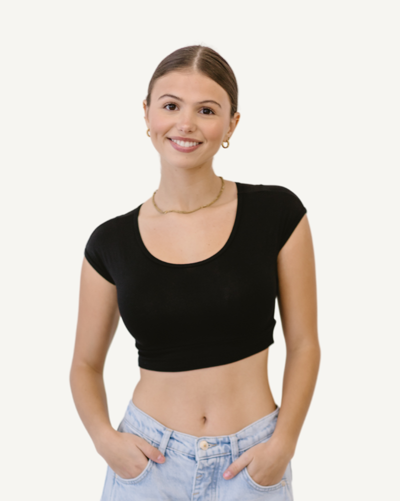 A fashionable woman wearing a black crop top and jeans, representing a best seller in trendy attire.