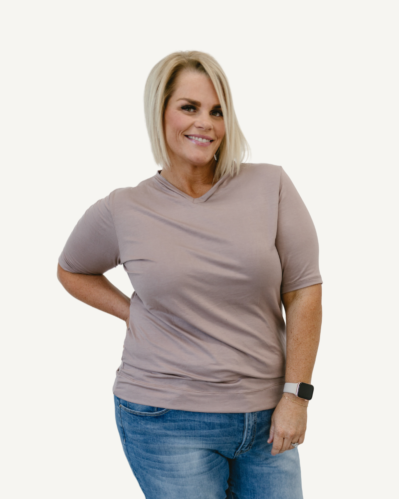 Woman in neutral shirt and jeans, standing confidently. Favorite Tee.