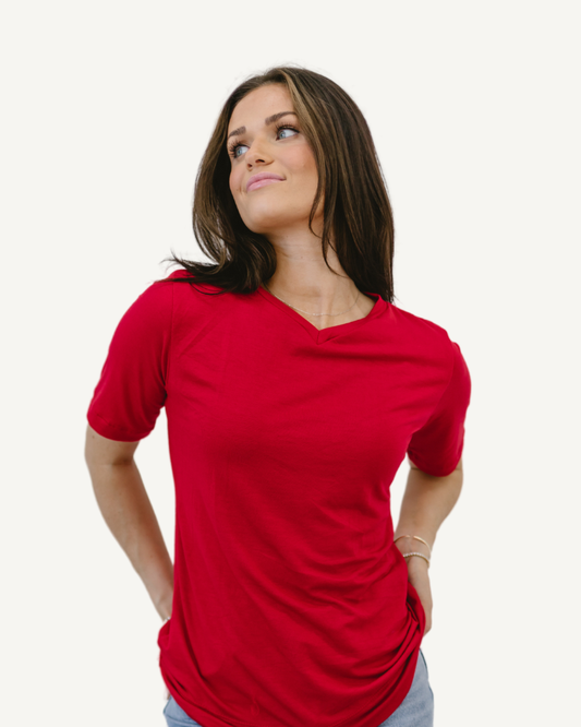 Woman in red shirt and jeans, standing confidently. Favorite Tee.