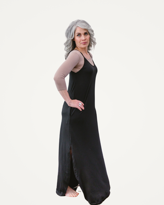 A woman wearing a black dress stands confidently