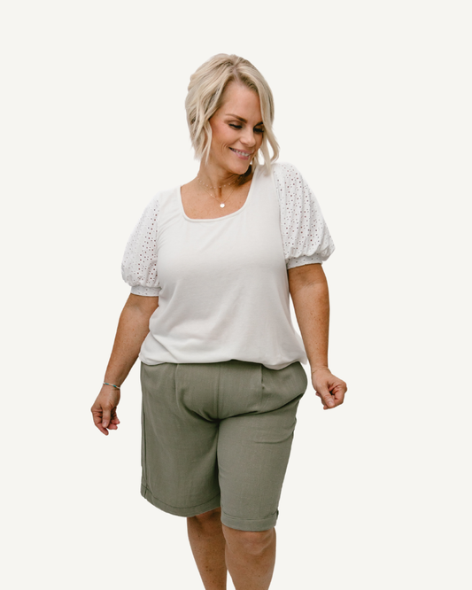 A woman wearing linen shorts, enjoying a sunny day outdoors.