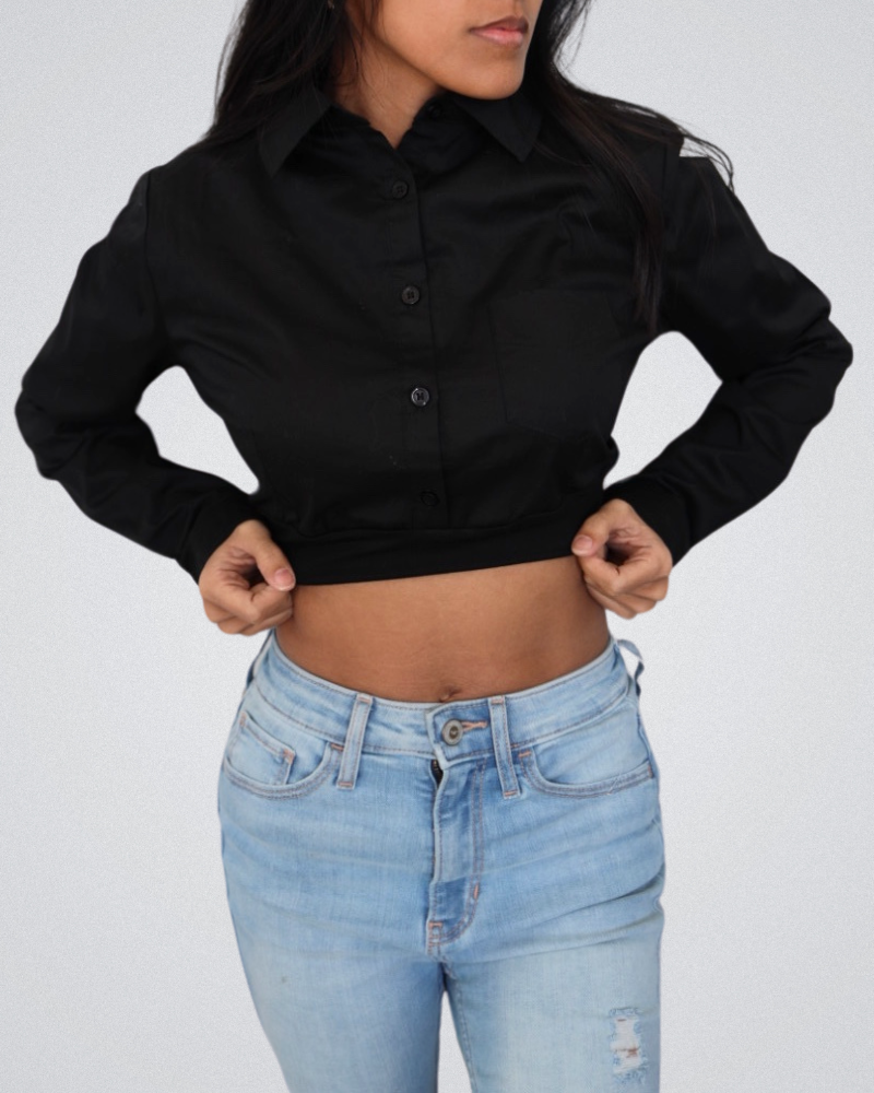 A woman dressed in a black crop top and jeans, embodying a chic and modern fashion statement.
