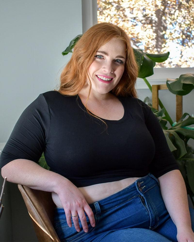 A woman wearing a black crew neck elbow sleeve top and jeans.