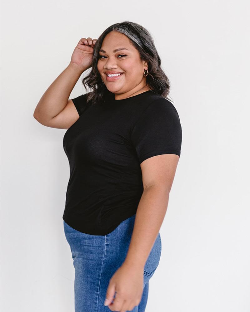 A woman wearing a black t-shirt and jeans, featuring a Crew Neck Boyfriend Full-Length - Layering Top.