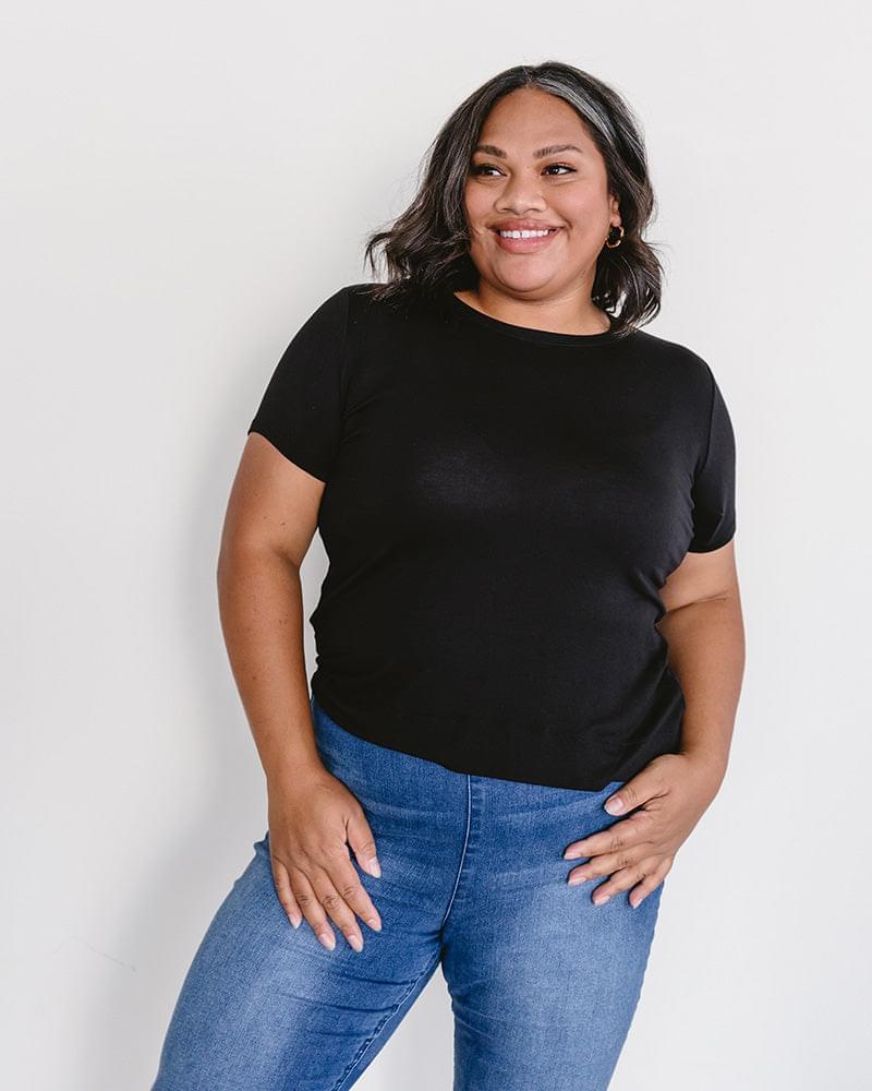 A woman wearing a black t-shirt and jeans, featuring a Crew Neck Boyfriend Full-Length - Layering Top.