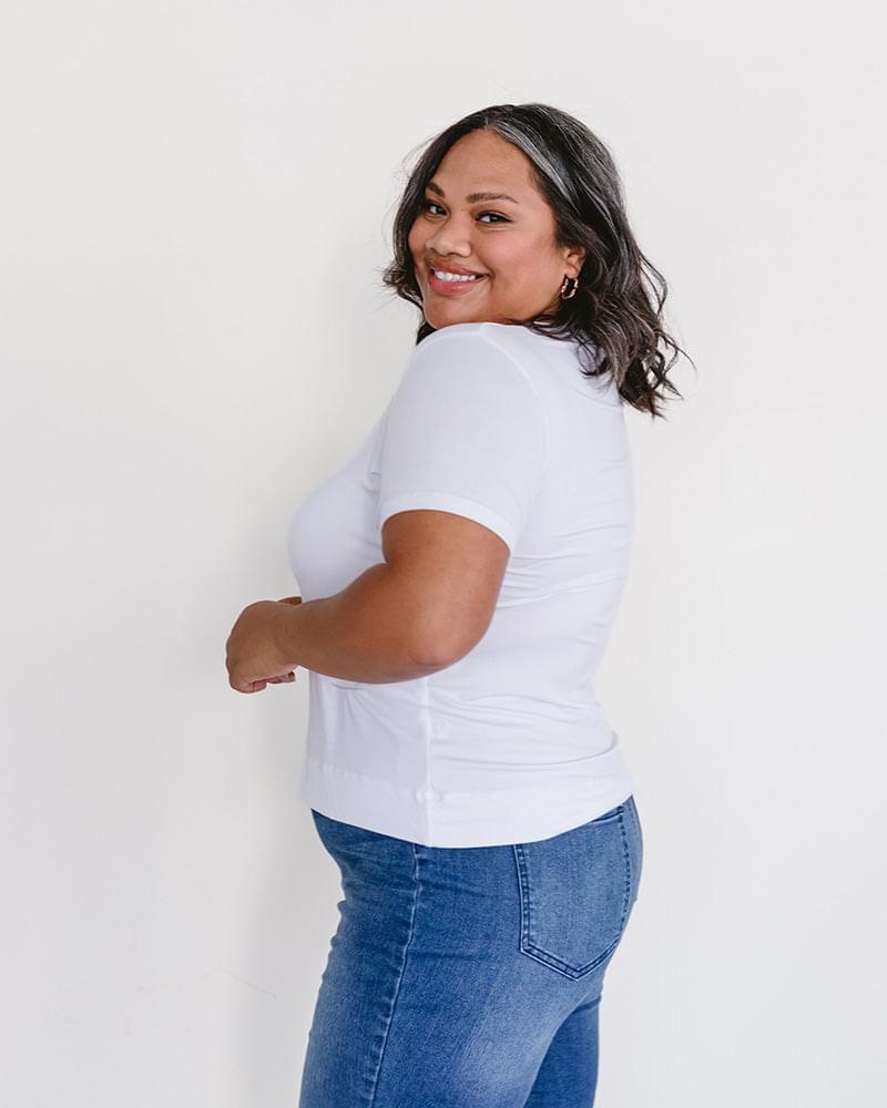 A woman wearing a white t-shirt and jeans, featuring a Crew Neck Boyfriend Full-Length - Layering Top.