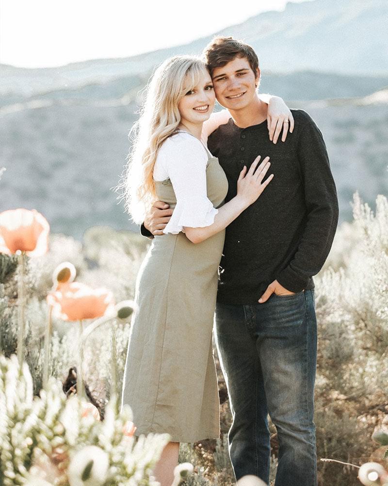 A couple standing in the desert surrounded by colorful flowers, wearing a Bell Sleeve Halftee.