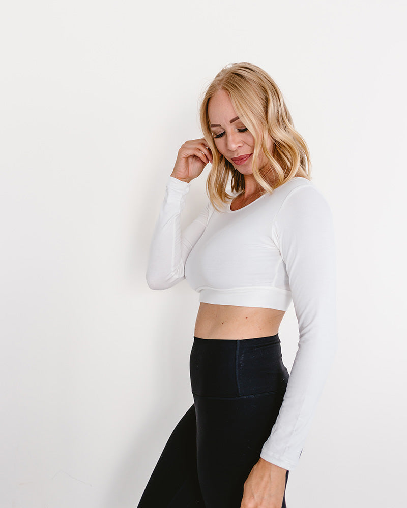 A woman in a white crop top and jeans, wearing a Classic Long Sleeve Halftee.