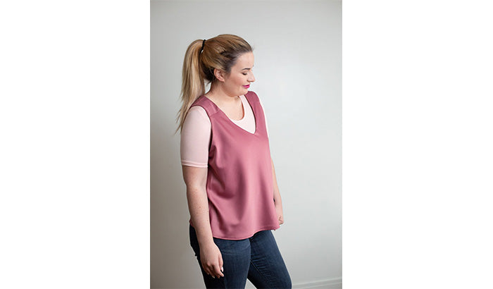 A woman in a pink top and jeans, showcasing a casual yet stylish everyday look with modesty in mind.