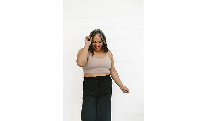 Woman in black crop top and wide leg pants, layered with base tee, camisoles, and mid sleeve shirt.