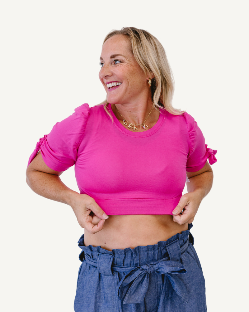 woman in a neon pink top and jeans, wearing a Puff Sleeve Halftee with Tie Detail.