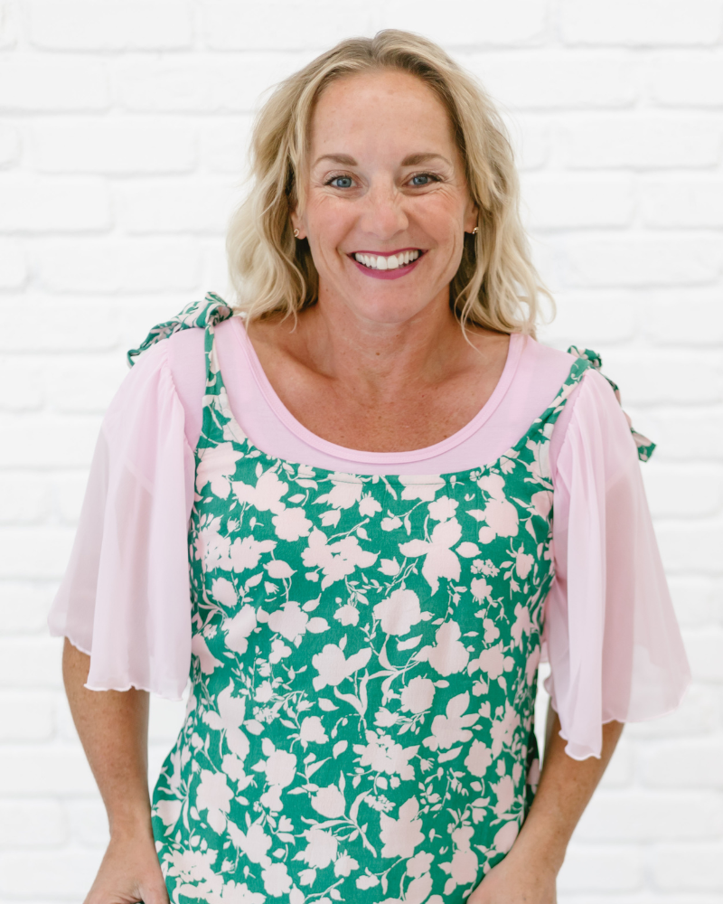 A woman in a green and pink floral dress, wearing a Waterfall Sleeved Halftee.