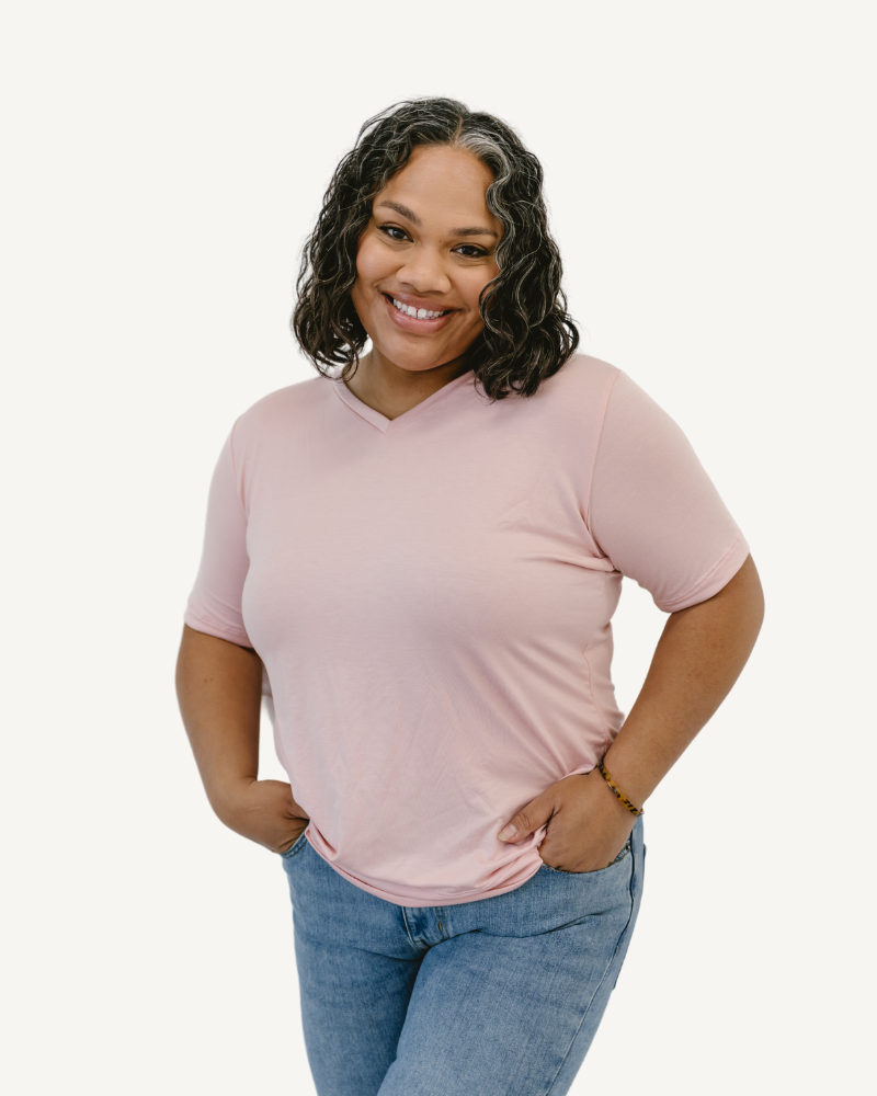  Woman in taupe shirt and jeans, standing confidently. Favorite Tee.