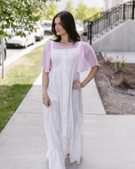 A woman wearing a white dress with pink sleeves, known as the Waterfall Sleeved Halftee.