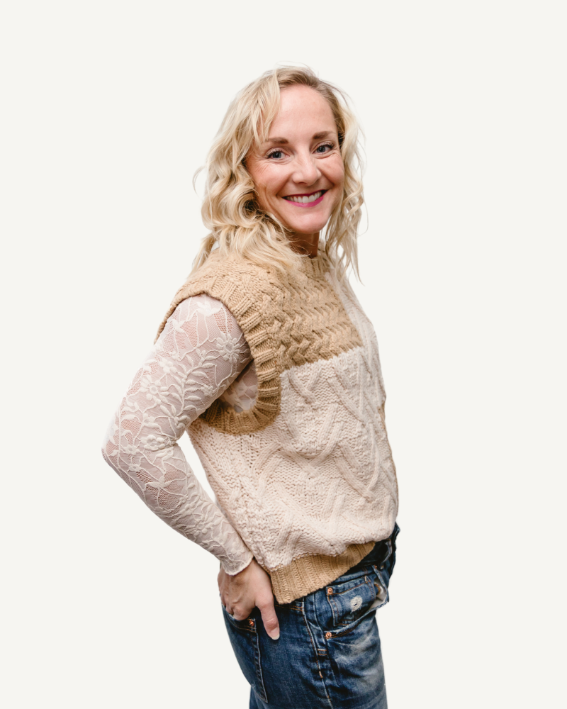 A woman in a black and white sweater and jeans, wearing a Full Lace Tank.