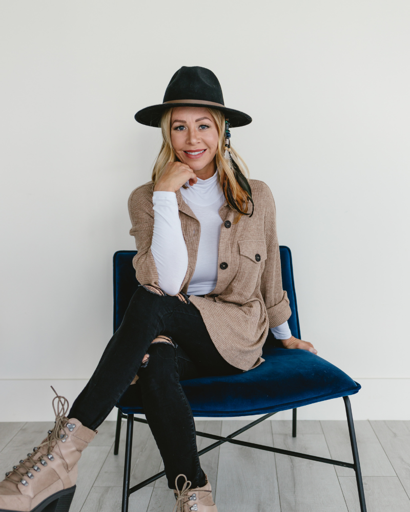 A woman in a hat and boots sitting on a chair, wearing a white Turtleneck Long Sleeve (Spandex/Rayon Blend).