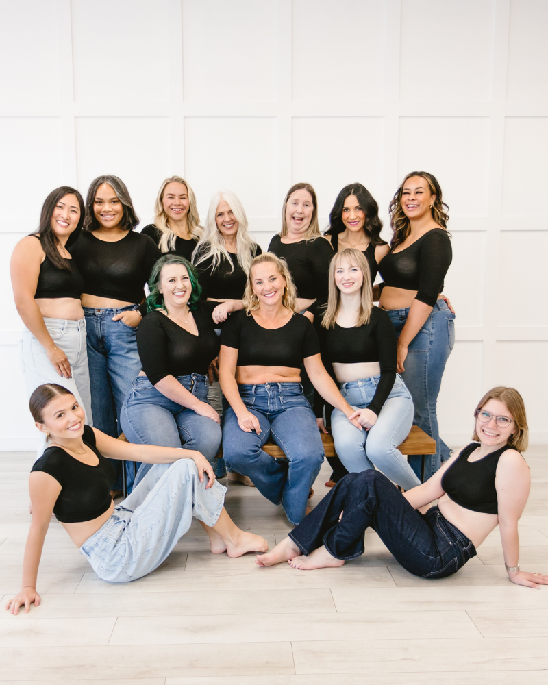 A diverse group of women in fresh blackshirts and jeans posing for a photo.