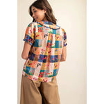 The model displays a colorful shirt and wide-leg pants, highlighting a fashionable and contemporary outfit choice.
