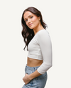 A woman wearing jeans and a white crop top with elbow sleeves and a V-neck.