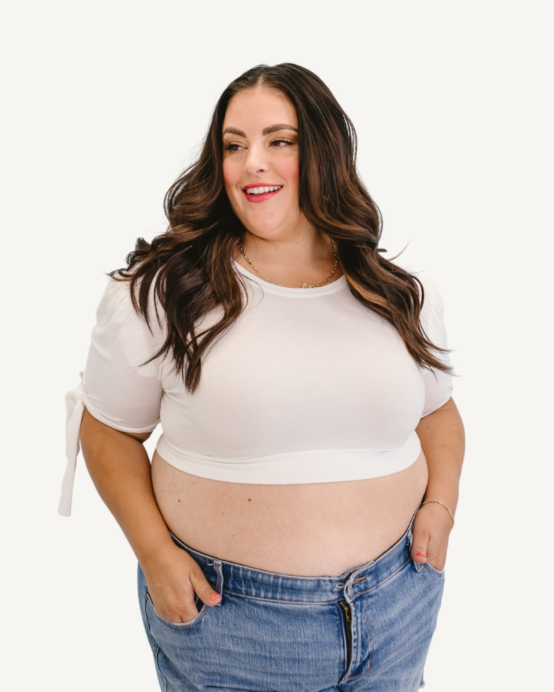 A plus size woman in a white top and jeans, wearing a Puff Sleeve Halftee with Tie Detail.