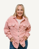 Woman in pink corduroy shirt and jeans, standing confidently. Ribbed Shacket.