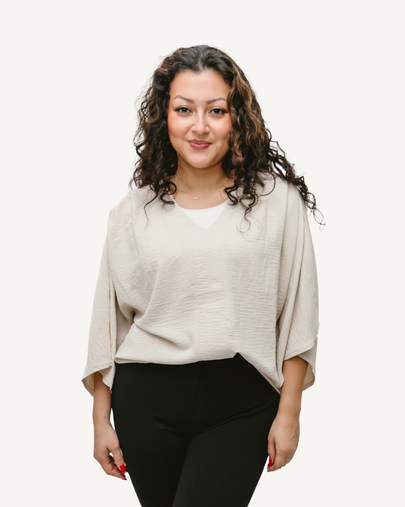 A woman wearing a beige top and black pants, showcasing a Flutter Sleeve Blouse.