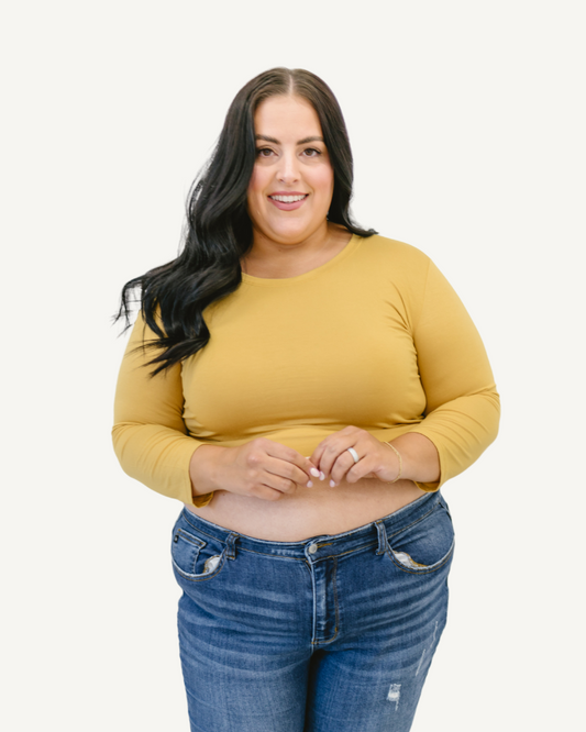 A plus size woman wearing a yellow crop top and jeans. (Discontinued 3/4 Colors)