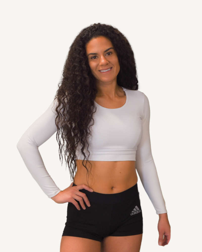 A woman wearing a white crop top and black shorts, showcasing the Brand New ATHLETIC Long Sleeve Halftee.