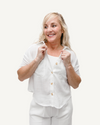 A woman wearing white pants and a linen-look short sleeve button-down shirt.