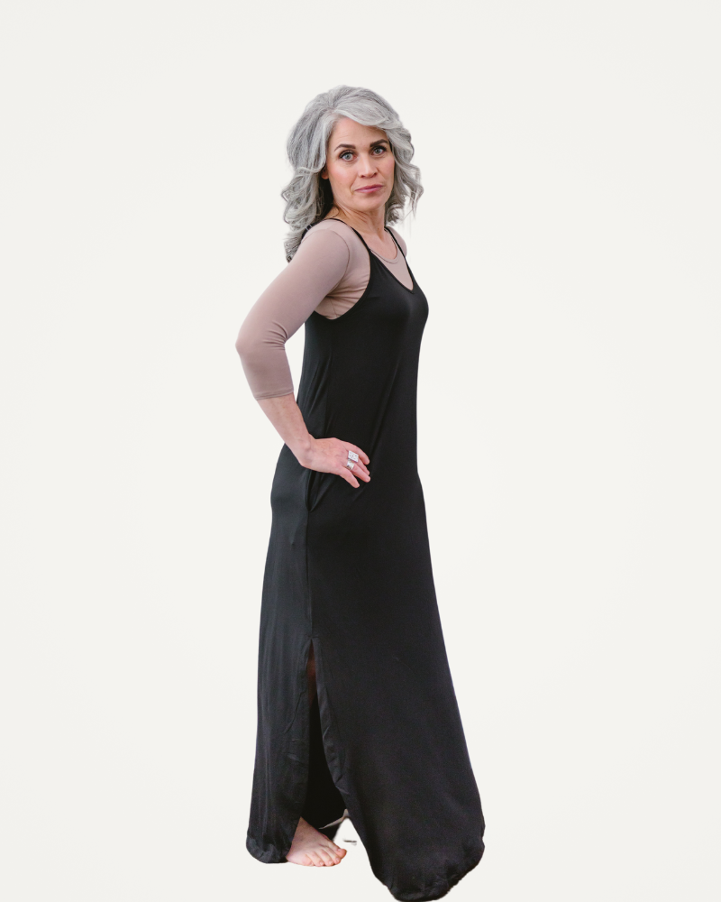 A woman wearing a black dress stands confidently 