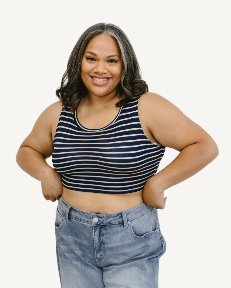 A girl wearing a striped crop top and jeans stands confidently, showcasing a casual and stylish outfit.