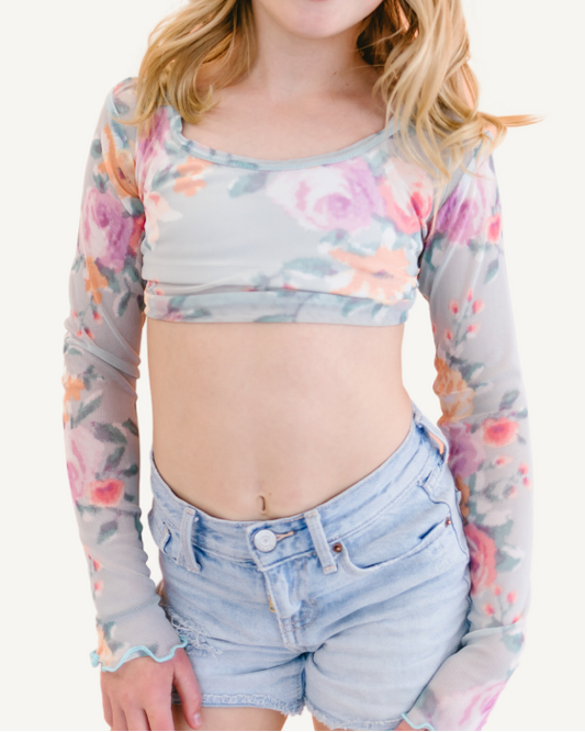 A young girl wearing a floral crop top called Girlee Long Sleeve Floral Mesh.