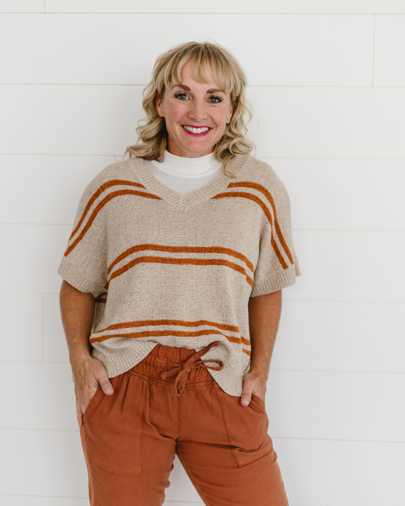 A woman in an orange pantsuit, smiling. She wears a Mock Neck Sleeveless Front top.