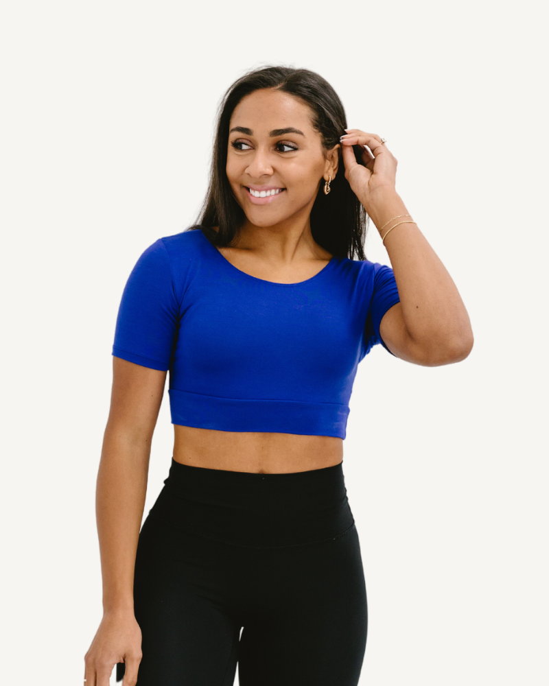 A woman wearing a bright blue crop top and black jeans, showcasing a trendy and vibrant style.