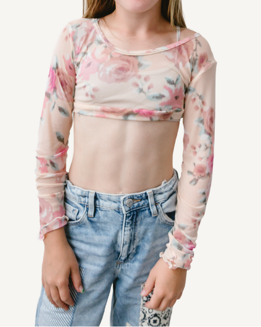 A young girl with glasses wearing a Girlee Long Sleeve Floral Mesh top.