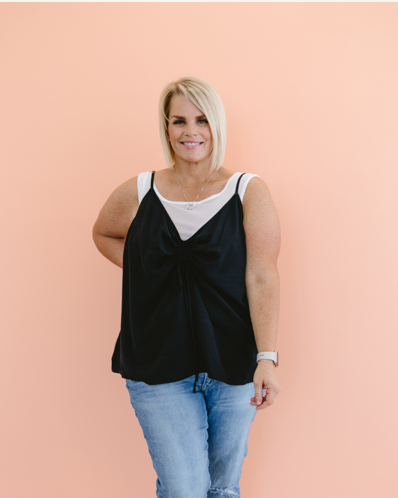 Woman in white mesh tank top and black leggings.