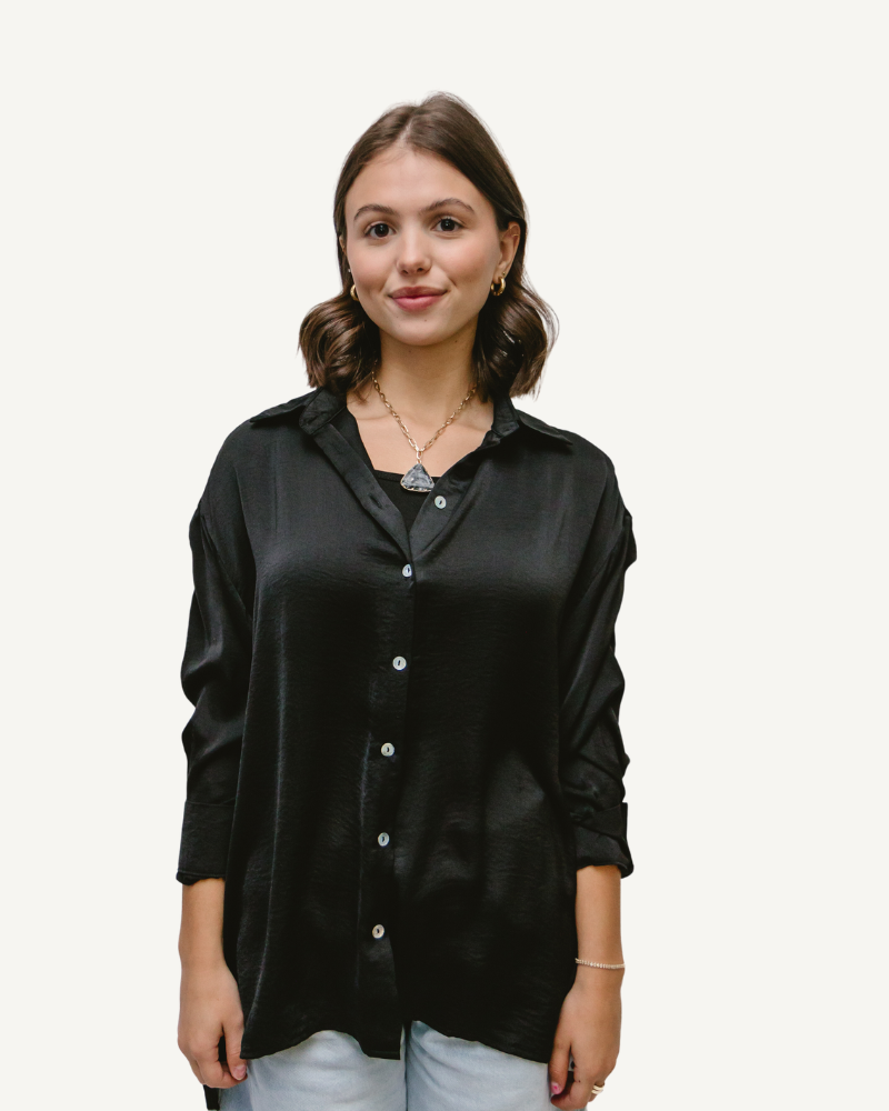 Woman in black satin button-down shirt and jeans.