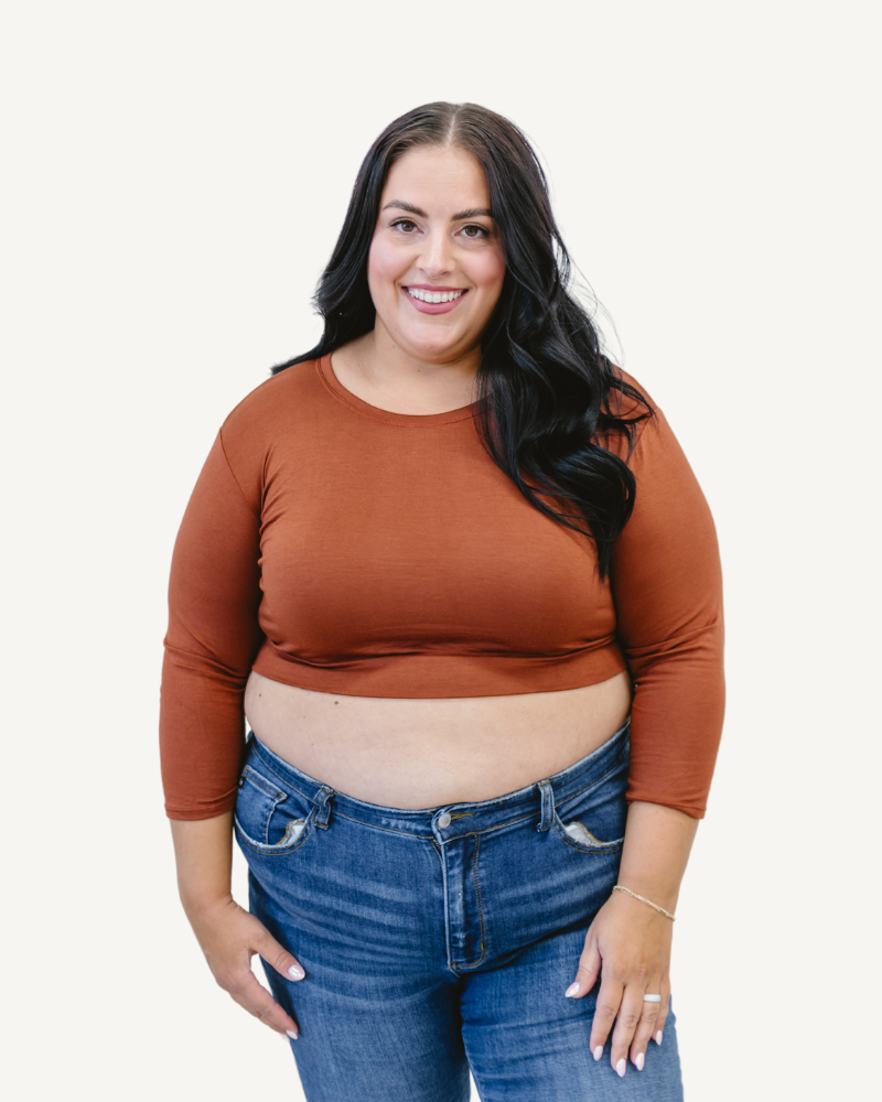 A plus size woman wearing a brown crop top and jeans. (Discontinued 3/4 Colors)