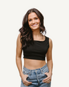 A stylish woman wearing an Elegant Tank, paired with jeans, showcasing a trendy crop top look.