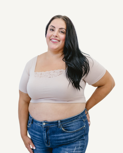 A curvy woman in a nude crop top and jeans, wearing a Peekaboo Short Sleeve Halftee with lace inset.