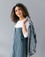 A curly girl wearing a denim jacket and dress 