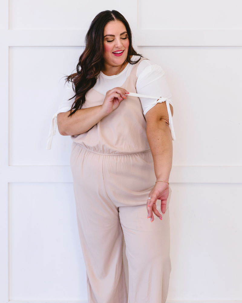 A plus size woman in a white top and jeans, wearing a Puff Sleeve Halftee with Tie Detail.