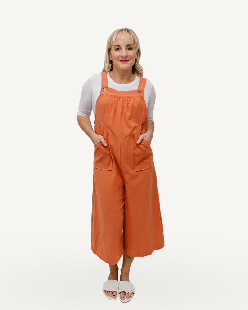 A woman in a cropped linen overall jumper striking a pose for the camera.