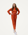 A woman dressed in an orange jumpsuit poses