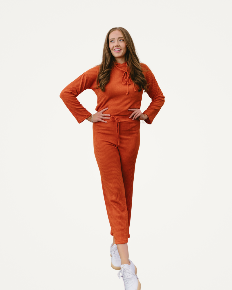 A woman dressed in an orange jumpsuit poses