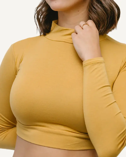 A woman wearing a yellow turtle neck sweater. She is also wearing a 'Mock Long Sleeve' garment.